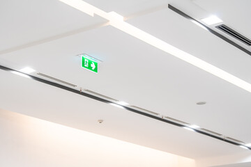 White neon sign depicting a fire exit with green background hangs from the ceiling.