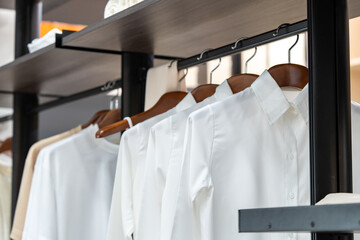 Shirts hang in a walking closet wiht beige and white T shirt on it.