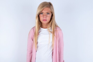 caucasian blonde little girl wearing pink jacket and glasses over white background frowning his eyebrows being displeased with something.