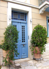 Fototapeta na wymiar Cozy classic design house entrance blue door, with potted plants. Athens old town center, Greece.
