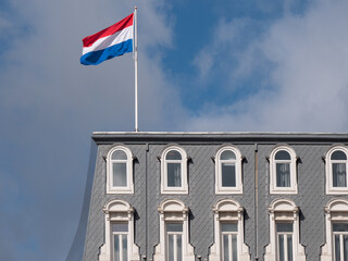 Fototapeta premium Dutch flag blows in the wind over the roof