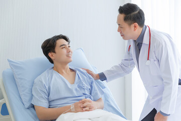 Obraz premium Senior doctor and young male patient who lie on the bed while checking symptom, consult and explain in hospital wards.