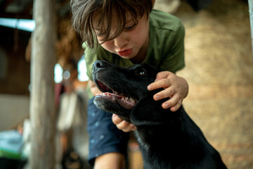 The boy lovingly hugs his pet, a cute black puppy.