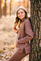 Young woman in hoodie smiling in an autumn park. Sunny weather. Fall season.