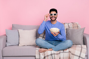 Full size portrait of positive satisfied person hand touch 3d glasses sit barefoot sofa isolated on pink color background
