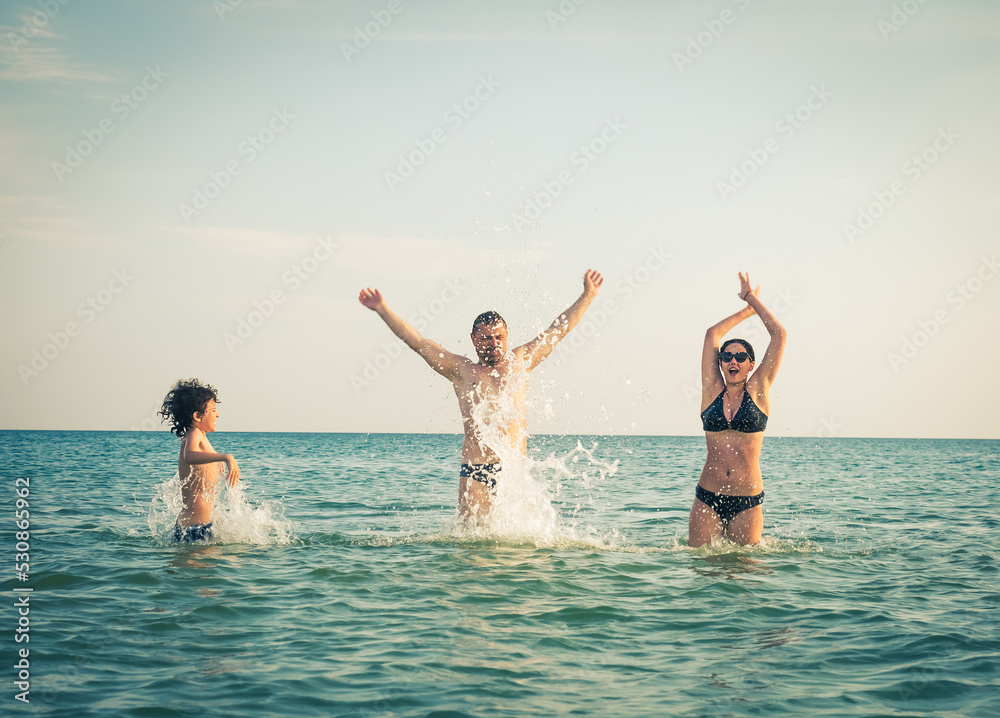 Wall mural Dad, daughter and son bathe swimming in the sea and having fun together. Paternity concept