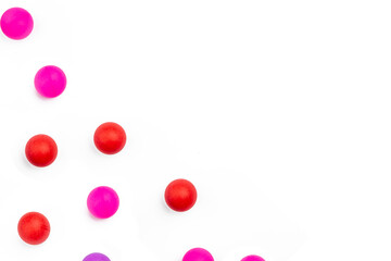 Abstract colored balls background. Red, pink taw toy scattered on isolated white background. Base for design nice backdrop, wallpaper, poster