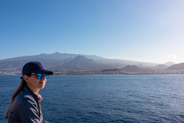 Fototapeta premium Woman enjoying the panoramic view from a ferry on the landscape around volcano mount Pico del Teide, Canary Islands, Spain, Europe. Boat is connecting Tenerife and La Gomera. Island hopping vacation