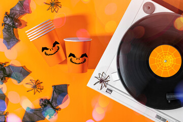 Halloween party background with Paper cup with Jack lantern face decoration, Halloween decorations, Vinyl records, party music, top view, spiders, bats, orange colors