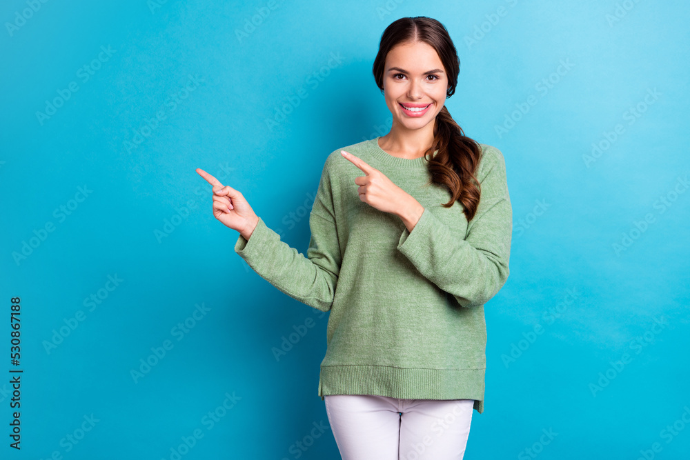 Poster portrait of positive lovely girl toothy smile direct fingers empty space offer isolated on blue colo