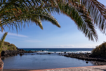 Fototapeta na wymiar Scenic sea view on beach Playa Charco del Conde from balcony of luxury apartment in Valle Gran Rey, La Gomera, Canary Islands, Spain, Europe. Tropical plants, palm trees in the foreground. Vacation