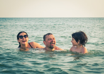 Dad, daughter and son bathe swimming in the sea and having fun together. Paternity concept