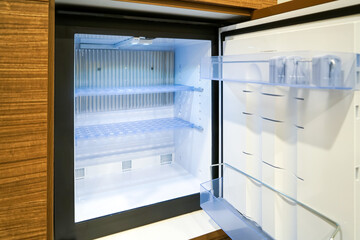 Black mini small fridge refrigerator under the frame wooden counter in hotel resort bedroom, or...