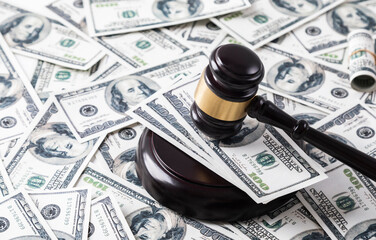 Wooden judge hammer and dollar bills