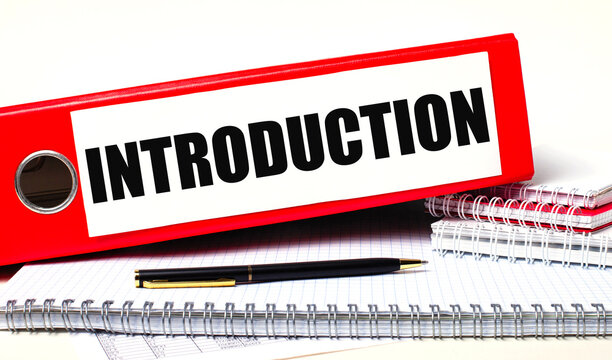 On the desktop are notebooks, a pen and a red folder for papers with the text INTRODUCTION. Business concept