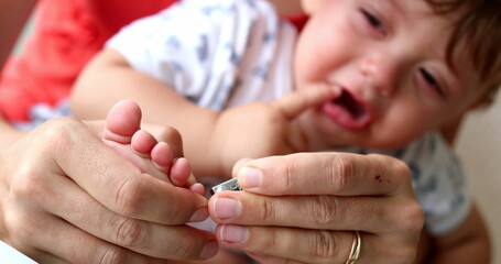 Mother trimming baby hand nail with clipper