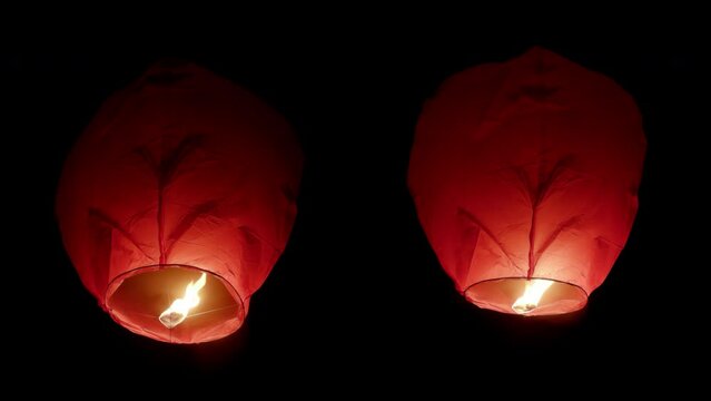 Two big fire paper lanterns floating in the night sky. Seamlessly looped, premultiplied, isolated on the black background with alpha channel, perfect for digital composition, cinema, motion design.
