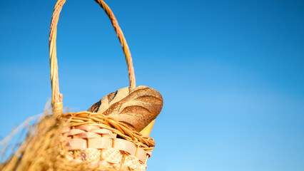 Basket with bread on a haystack against the sky in an open space. Harvest concept