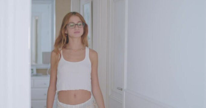 Young alluring lady walking in hall of apartment