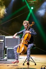 Fototapeta premium Young woman playing cello on the concert stage at night
