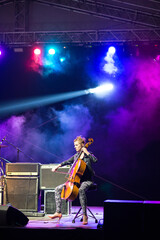 Young woman playing cello on the concert stage at night