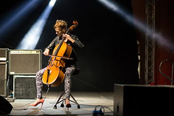 Young woman playing cello on the concert stage at night