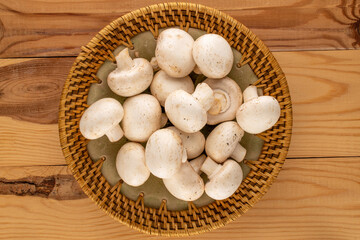 Several aromatic organic mushrooms with ceramic plate on wooden table, close-up, top view.