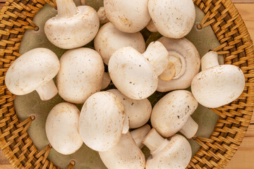 Several aromatic organic mushrooms with ceramic plate on wooden table, close-up, top view.