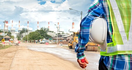 An engineer holding a white helmet stands in front of the job.