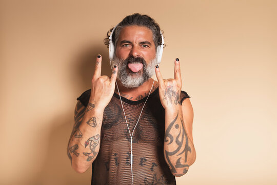 Bearded man showing rock gesture and listening to music