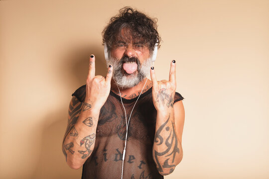 Bearded man showing rock gesture and listening to music