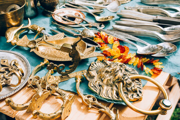 Antiques on flea market or car boot sale - vintage silver and cooper dishes, cutlery set, door lion...