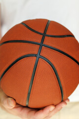 Red basketball in the hands of a close-up on a white background