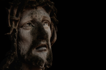 Fototapeta na wymiar Antique stone statue Jesus Christ in a crown of thorns aagainst black background. Copy space.