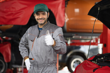 Portrait automobile mechanic man standing showing thumbs up with looking at camera. diagnostic and repairing vehicle at garage automotive, Car care check and fixed and services insurance concept.