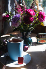 A cup of tea with bouquet of aster flowers, morning tea concept.