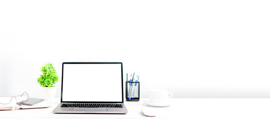 Blank white screen laptop on a white table in the office. A working concept using technology, notebook, smartphones, devices. Copy space on right for design or text, Closeup, Gray, and blur background