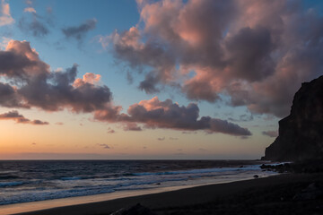 Scenic view during sunset on the volcanic sand beach Playa del Ingles in Valle Gran Rey, La Gomera, Canary Islands, Spain, Europe. Massive cliffs of the La Mercia range. Close up on Rock formation