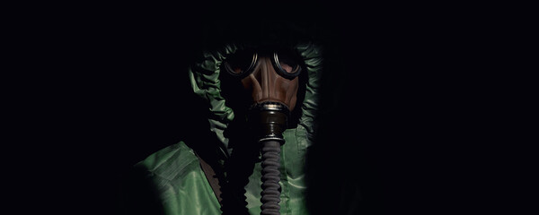 Portrait of person in gas mask and green protective costume isolated on black background closeup
