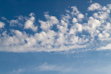 White cumulus clouds on a clear blue sky.