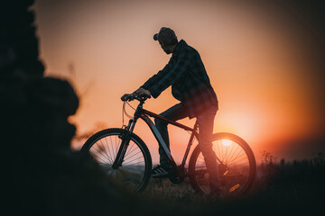 A silhouette of a guy riding a bicycle against a stunning pink sky at sunset. The vibrant colors create a dreamy atmosphere, capturing the essence of freedom and adventure in the open air.