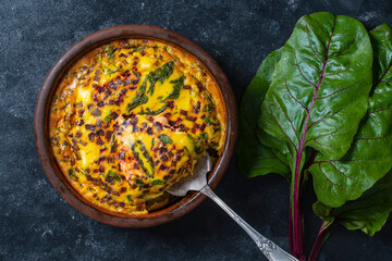 Ceramic bowl with vegetable frittata. Frittata with eggs, green beet leaves, onion, pepper, spices and cheese