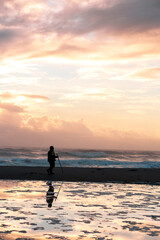 Fototapeta premium Silhouetted man walking down the beach during sunrise