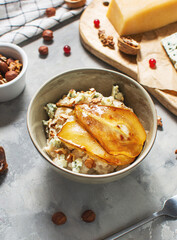 Pear and gorgonzola oatmeal with walnuts on concrete table