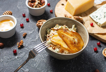Pear and gorgonzola oatmeal with walnuts on black stone table