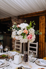 Beautiful multi-colored flowers in a glass vase are on the table. Wedding decorations, close-up photography.