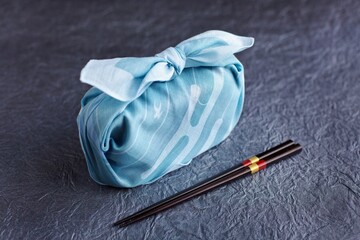A bento box wrapped in beautiful cloth, with chopsticks. 