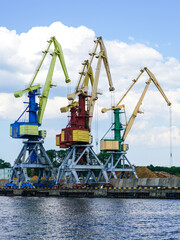 Harbor pier with many shore cranes and stacks of bulk cargo, coal and wood chips