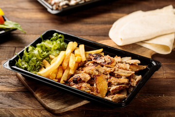 Chicken Shawarma plate with salad, fries and pita bread served in a dish isolated on wooden table background side view of fastfood