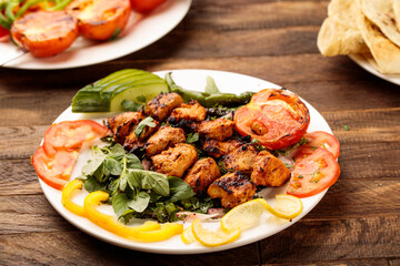 Chicken Grill Tikka boti kabab with tomato, salad and bread served in a dish isolated on wooden table background side view of fastfood